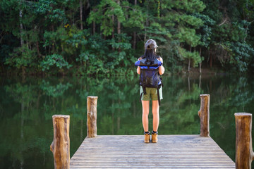 woman backpacker travel on the forest waterfront river, explore the jungle forest in summertime vacation trip