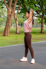 Beautiful woman doing stretch exercise stretching her arms at park.