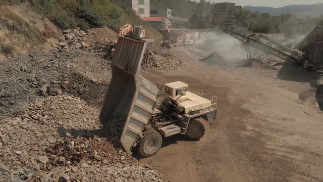 Dump truck unloading the coal at quarry. Heavy machinery working at stone quarry in summer.