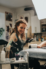 girl with dreadlocks and tattoos stuffs tattoo leg