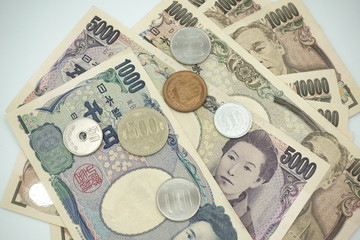 Close up of variety of Japanese yen currency banknotes and coins lay flat as background.