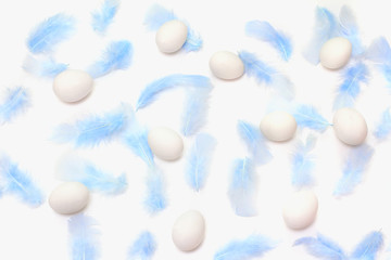 Easter pattern. light blue feathers and eggs on a white background. flat lay, top view