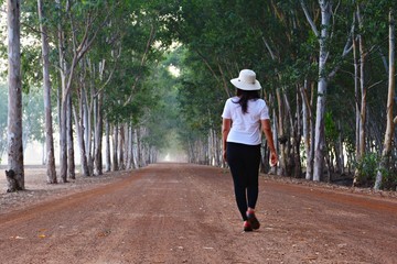 Thai woman walking on a dirt road With a tree tunnel in the background