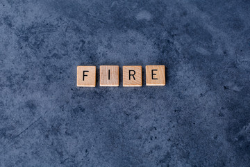 "FIRE" (Financial Independence, Retire Early) spelled out in wooden letter tiles on a dark rough background