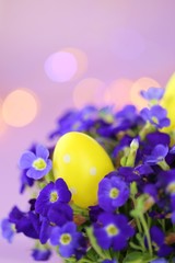 Easter holiday.Yellow easter eggs in bright violet colors on a light purple background with  bokeh.Spring festive bright background.