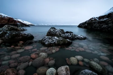 schneebedeckte, weiße Küste des Arktischen Ozeans, mit Wellenschlag an großen Felsen © Павел Чигирь