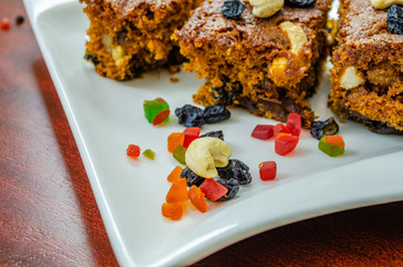 Close up of dry fruits with the slices of plum cake in the background.