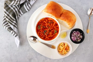 Spicy Misal Pav or usal Pav is a traditional snack or Chat food from Maharashtra, India. Served with chopped onion, lemon wedges and farsan. Selective focus with copy space