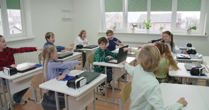 Education in the modern school, a boy uses a laptop during a lesson at school, bullying at school, children point fingers at the student.
