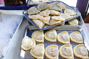 Raw curry puffs are on stainless trays before frying in oil in Thailand.