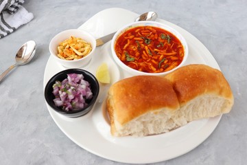 Spicy Misal Pav or usal Pav is a traditional snack or Chat food from Maharashtra, India. Served with chopped onion, lemon wedges and farsan. Selective focus with copy space