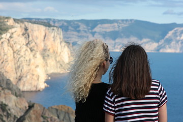 girls on the rocks by the sea admiring the natural scenery