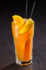 Fresh exotic cocktail with ice cubes and orange on a wooden table