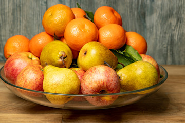 Naklejka na ściany i meble Apples, pears and tangerines in a plate on a wooden background.