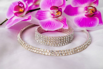 Bracelet and necklace on white fabric and purple Orchid