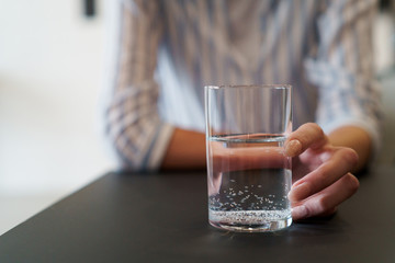 female holding glass with still water