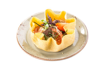 Beef salad with mixed vegetables served in tortilla bowl isolated on white background