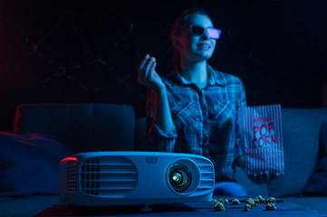 The girl watches movies on the couch with popcorn. Cinema and films. Home cinema. Watching films at...