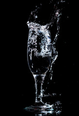 Water with splashes in a glass on a black background