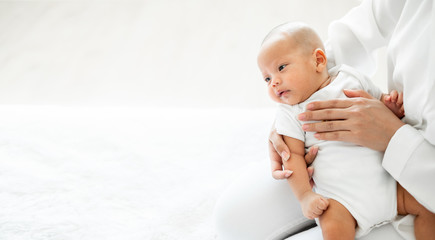 Young Asian mother holding her newborn baby with love on white bed, mother's day concept, banner...
