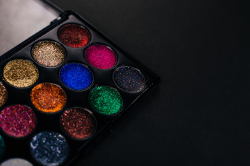 Palette with multi-colored sequins for the eyes. Eye shadow on a black background. Makeup artist tool