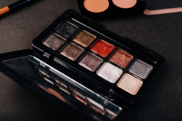 Palette of old eye shadow on a black background. The contents of a handbag. Makeup brush tool. Dusty makeup
