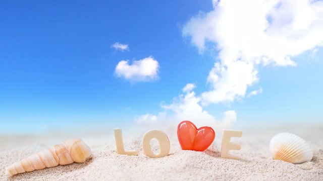 red Heart shape and love wooden text on white sand beach with tropical blue sea and cloudy blue sky