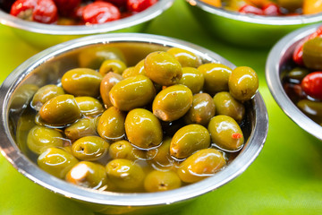 Green olives piled in metal plates.