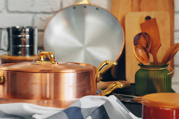 Copper cookware with wooden kitchen utensils close up