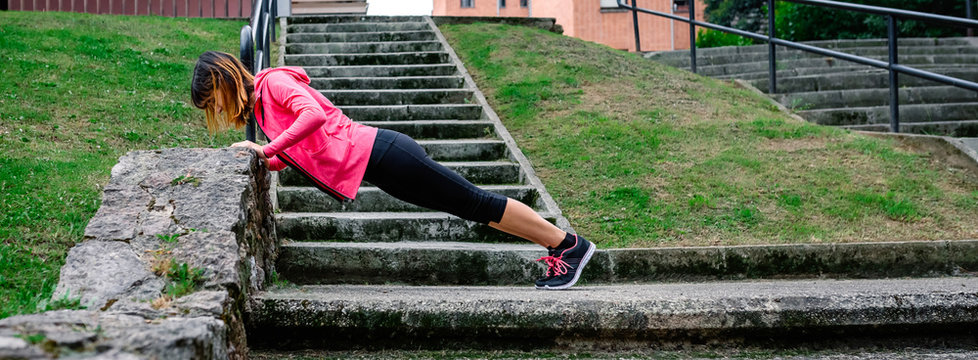 Young female athlete doing push-ups supported on a wall outdoors