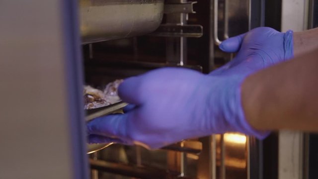 closeup of chef hand putting metal container with baked chicken in white sour cream sause in buffet cafeteria. cook preparing food. appetizing meat. canteen catering business concept