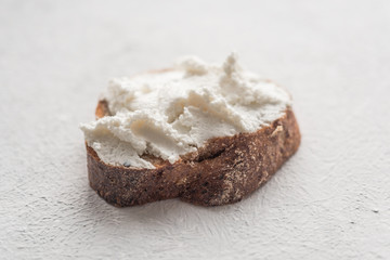 Whole grain bread bruschetta with white soft curd cream cheese on a white background. Close-up