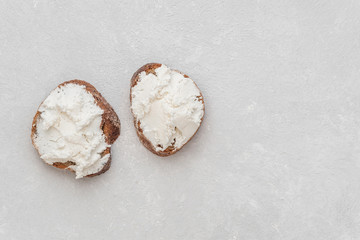 Fototapeta na wymiar Whole grain bread bruschetta with white soft curd cream cheese on a white background. Top view. Close-up
