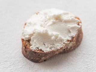 Whole grain bread bruschetta with white soft curd cream cheese on a white background. Close-up