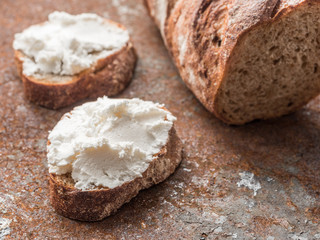 Whole grain bread bruschetta with white soft curd cream cheese on a ginger grunge background. Close-up