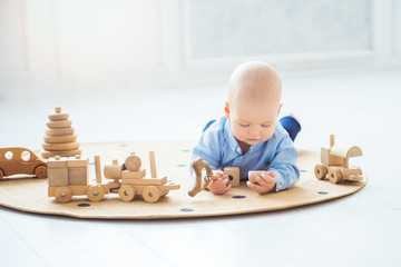 Baby boy playing with wooden toys lying on the Mat. Ecology, education, upbringing concept