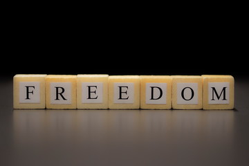 The word FREEDOM written on wooden cubes isolated on black background