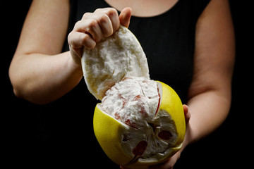 Pomelo citrus fruit with sweet red flesh and yellow thick rind on black background. Fresh juicy...
