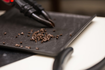 Preparing a strand of hair for extension. Hair and hair tools close-up.