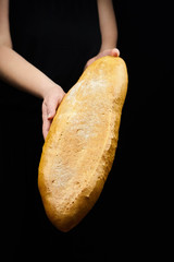 Sourdough bread, bakery product on black background. Woman holds white wheat bread. Female hand and bun