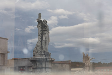 Statues reflected on a glass in a cemetery