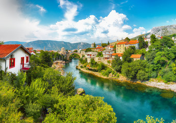 Fantastic Skyline of Mostar with the Mostar Bridge, houses and minarets, during sunny day.