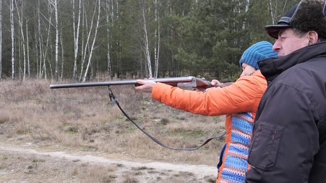 Beautiful woman shoots a hunting rifle in nature