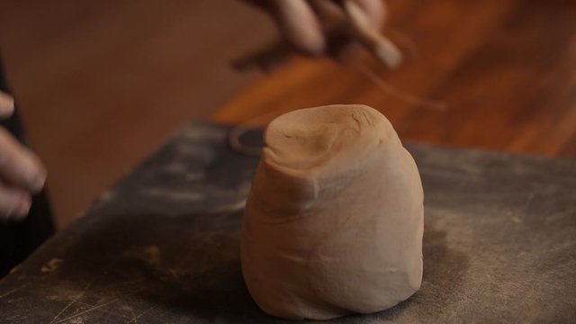 A man kneads clay in a pottery workshop. Male hands closeup knead clay. Clay modeling workshop.