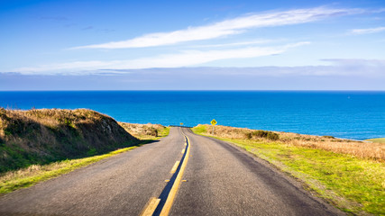 Winding road on the Pacific Ocean coastline on a clear sunny day, Point Reyes National Seashore,...