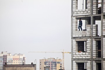 construction of a new house with a builder in the window on a background of gray sky