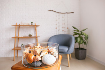 Vase with sea shells on table in room