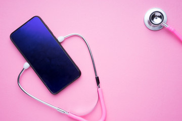 Technology in women healthcare concept. A pink stethoscope and a smartphone on a pink background. Landscape orientation.