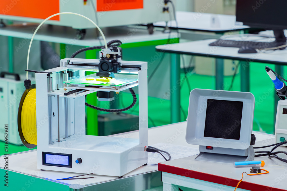 Poster 3d printer stands on a table in a laboratory. 3d printer with a yellow cartridge. equipment for thre