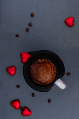 That's ground coffee in a strainer over the cup on a dark background with grains and red hearts. The top view. Flat lay.